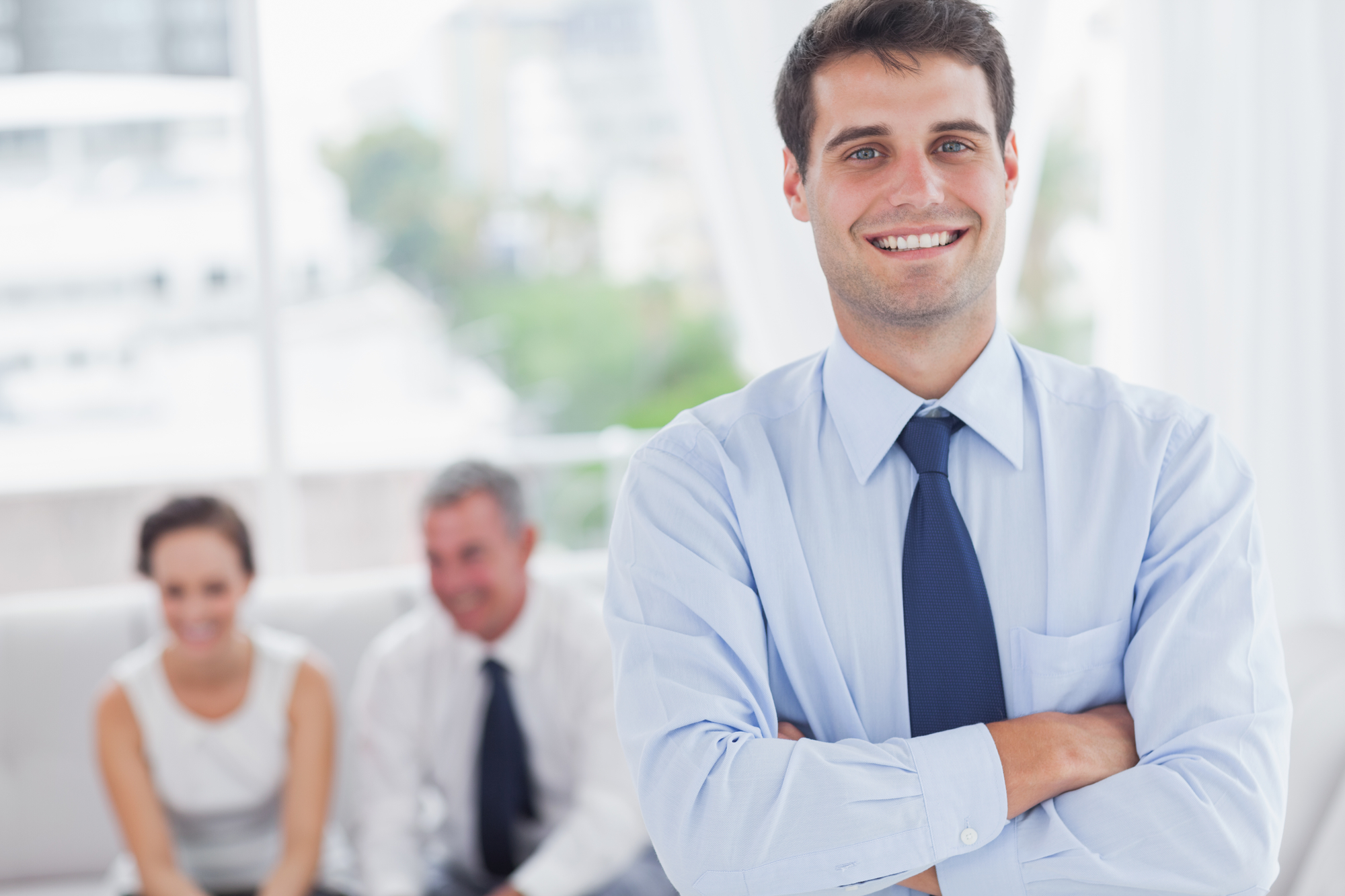 Cheerful businessman posing while his colleagues are working in cosy meeting room